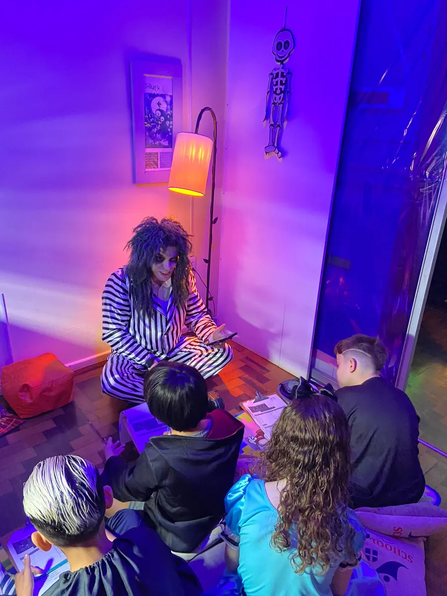 Crianças ouvindo uma história de Halloween na sala decorada com luz roxa