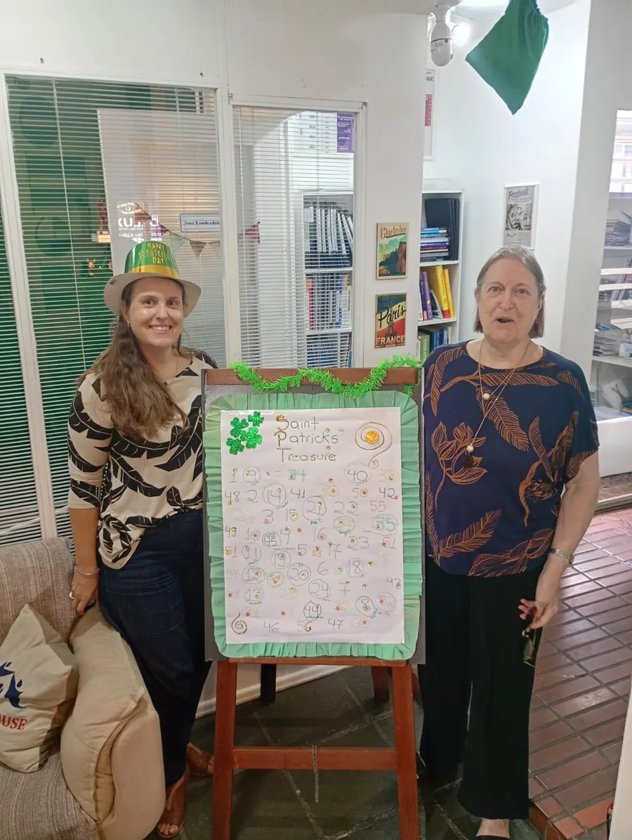 Duas mulheres ao lado do quadro do St. Patrick's Day na recepção da escola