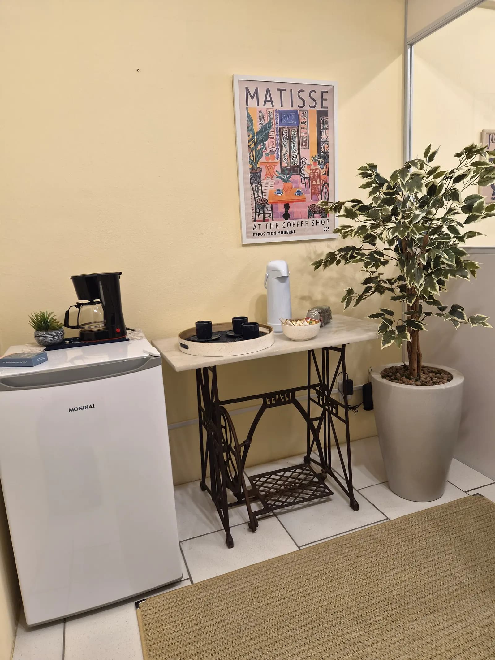 Cantinho do café da sede de Guaíba, com cafeteira, frigobar e planta