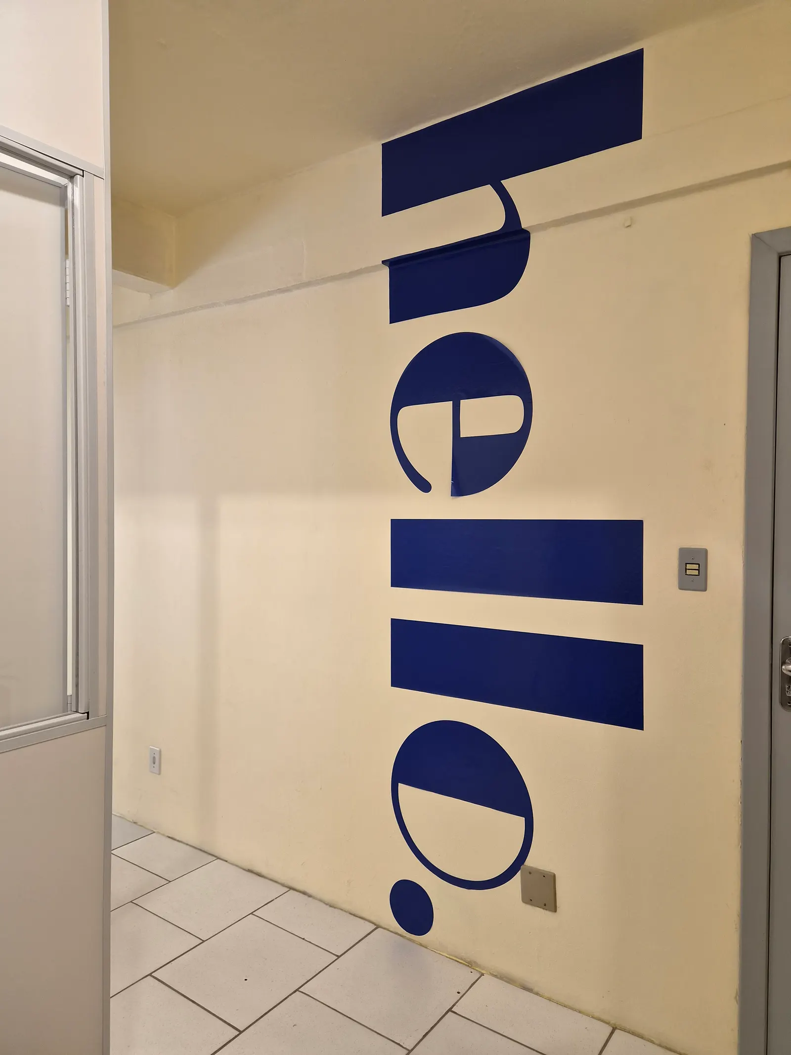 Parede com a palavra hello pintada em azul no corredor da sede de Guaíba