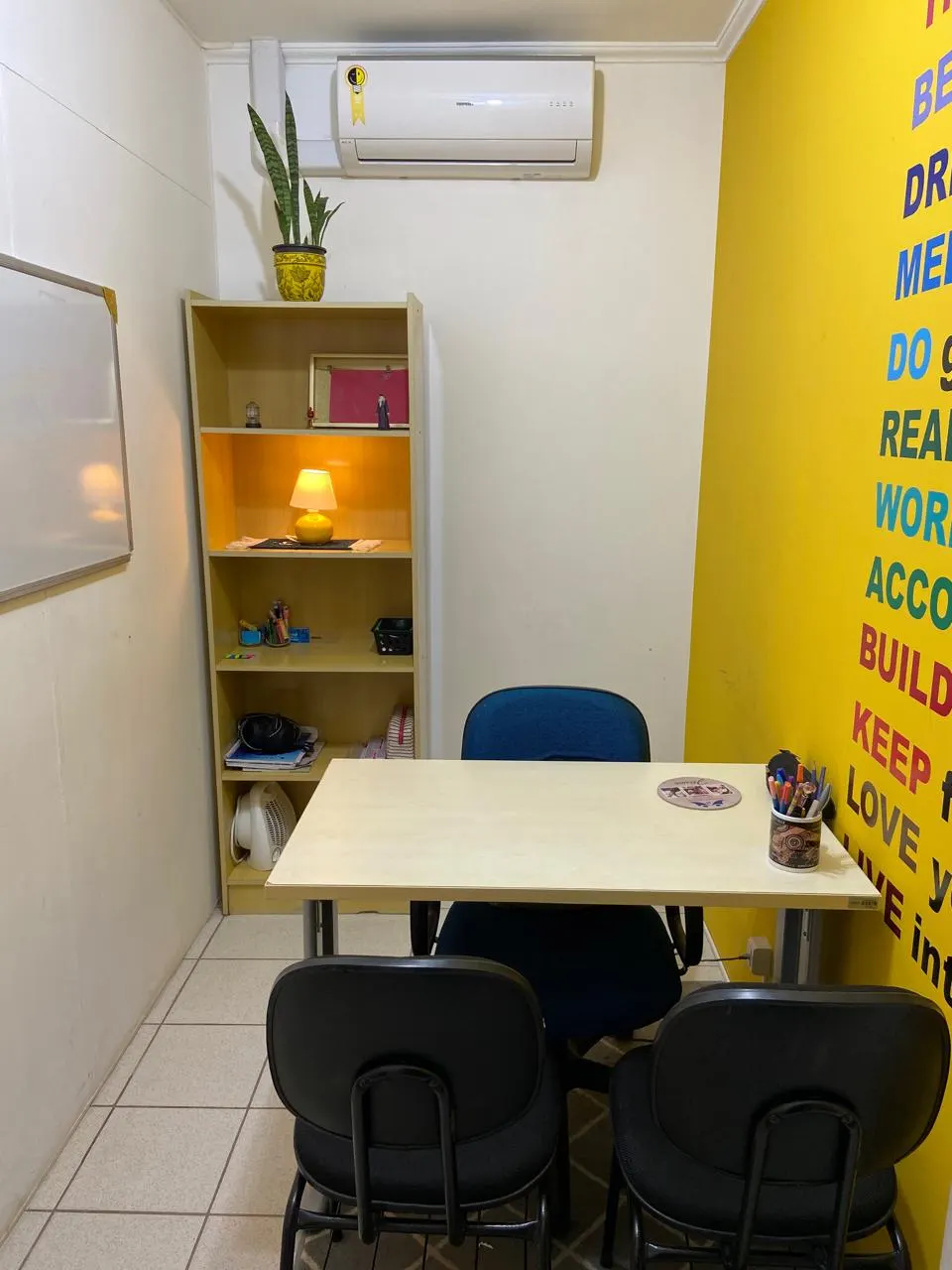 Sala individual da School House com parede amarela de frases em inglês